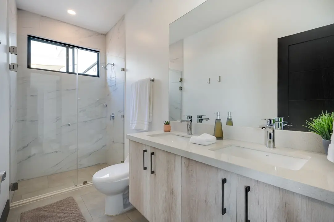 Modern Tamawalk bathroom with marble tiles, double sinks, a spacious shower, and plenty of natural light.