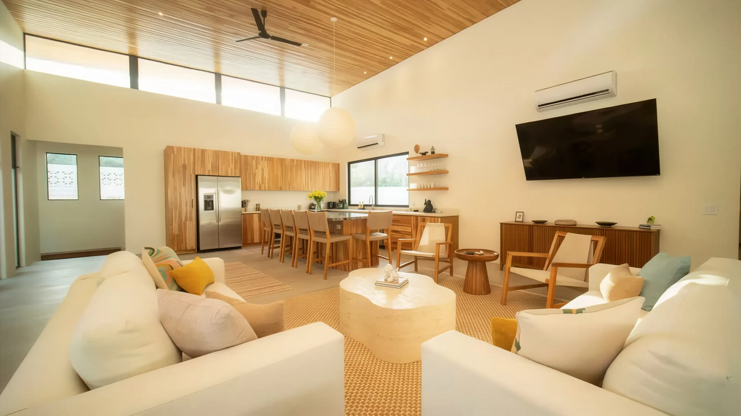 Representación 3D del interior del área social de la Casa CM, con un diseño contemporáneo que destaca por el techo de madera, ventanales de piso a techo y una distribución abierta que integra sala, comedor y cocina. Los acabados cálidos y naturales brindan confort, elegancia y una conexión visual con el jardín exterior.