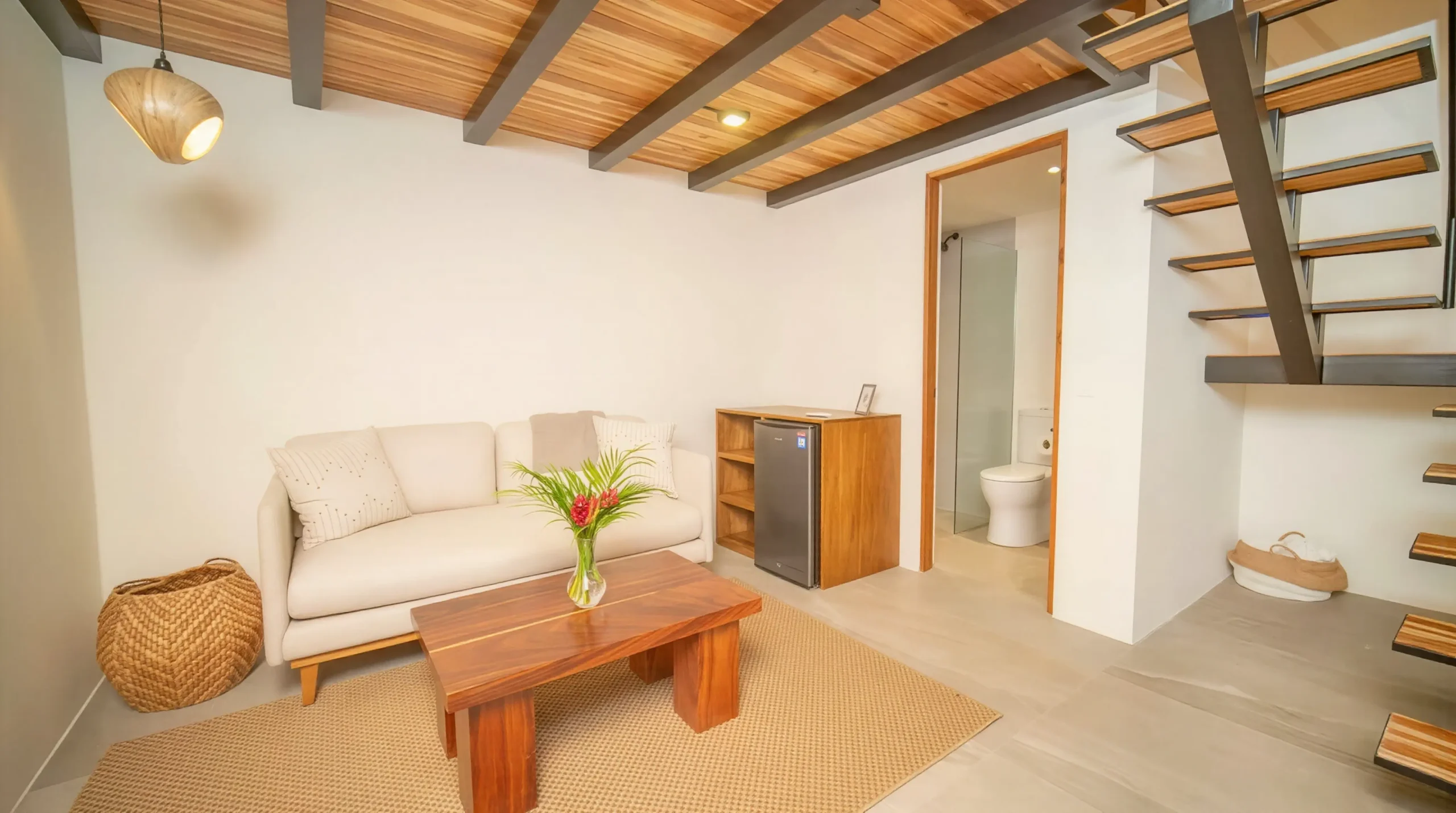 Bright and minimalist living room in House Corona's guesthouse, featuring modern furniture combining wood and metal.