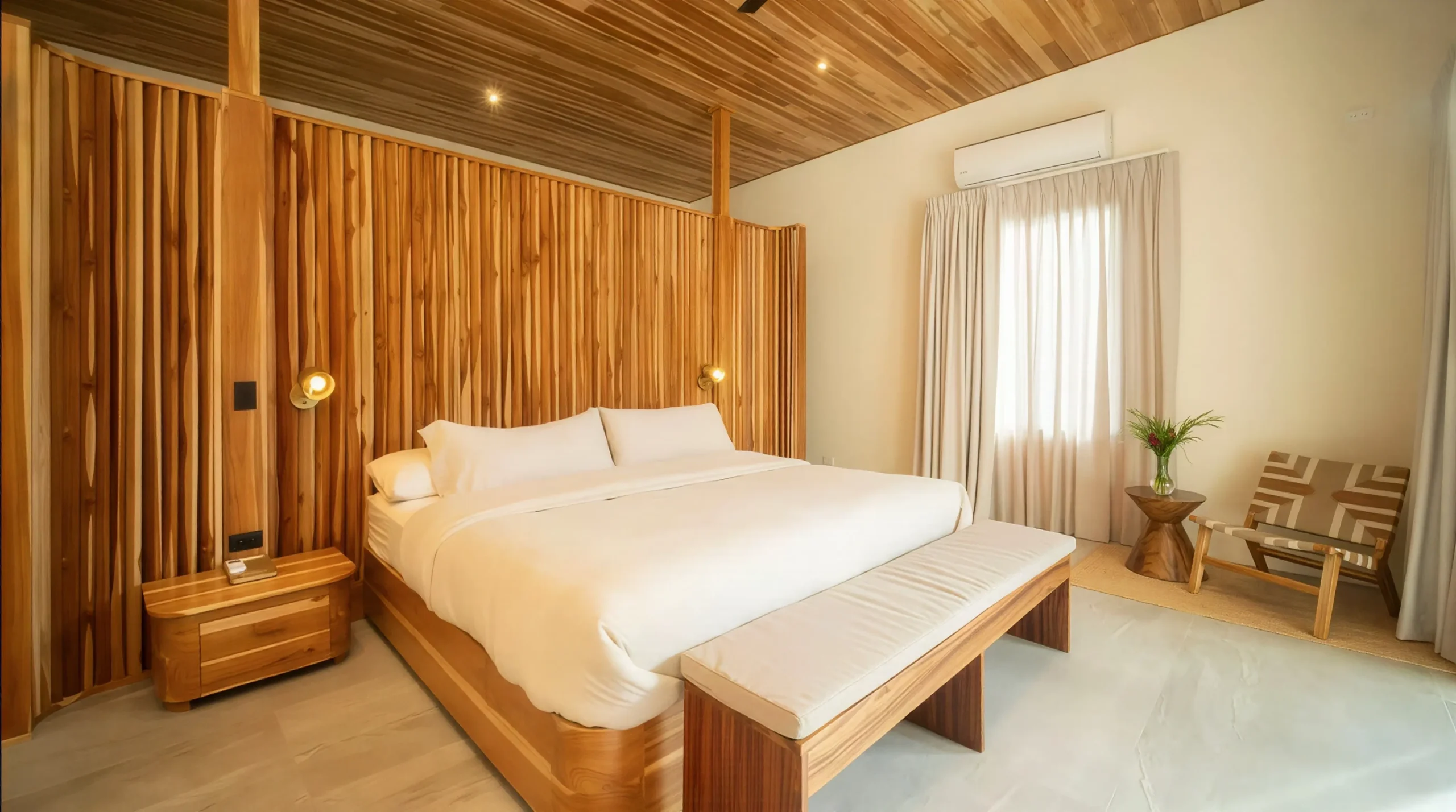House Corona's master bedroom features a cozy bed with a wooden headboard, soft lighting, and a minimalist design that invites relaxation.