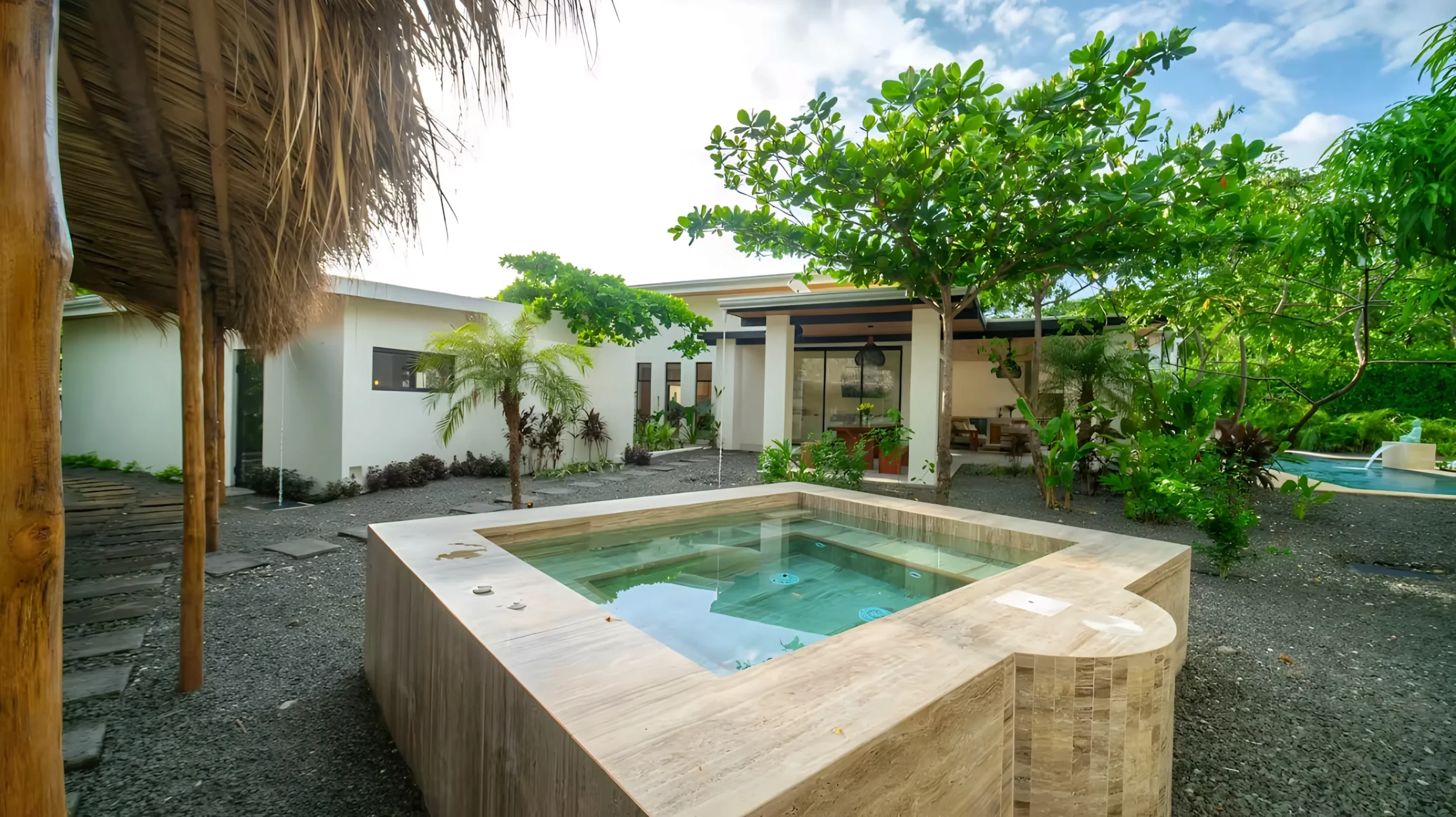 House Corona's plunge pool, surrounded by gravel and vegetation, with the main house in the background.