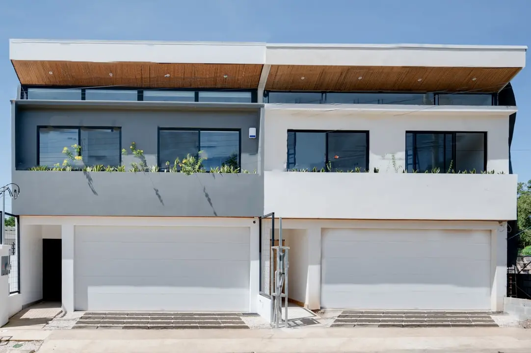 Tamawalk's modern facade, featuring a clean, two-story design, a garage, generous windows, and plant details.